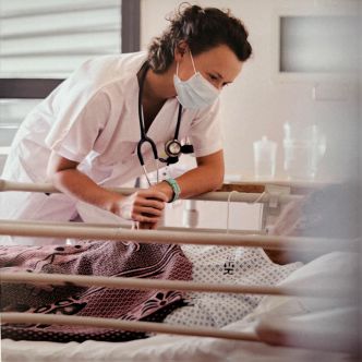 Une femme médecin portant un masque et tenant la main d'une personne allongée